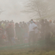 Spectators stand in the dust.